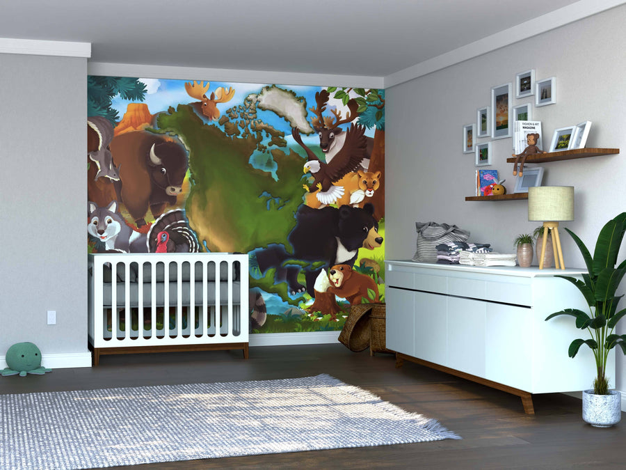 A nursery with a white crib and dresser features the vibrant Nature’s Creatures Wall Mural of forest animals behind the crib. Shelves with decor, framed photos, a potted plant, and hardwood floors complete the charming space.