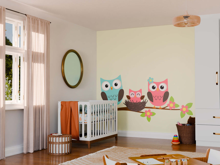 A cozy nursery with wooden floors, a white crib, and a round mirror. The "Owls in a Cozy Nest Wall Mural" adds color above the crib. Soft light filters through beige curtains, while toys stay organized in baskets.