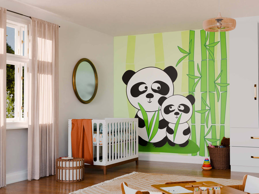 A nursery featuring a Vector Panda Wall Mural with two pandas and bamboo, a white crib with orange bedding, round mirror, wicker basket, colorful rings on the wooden floor, and sunlight streaming through tall window curtains.