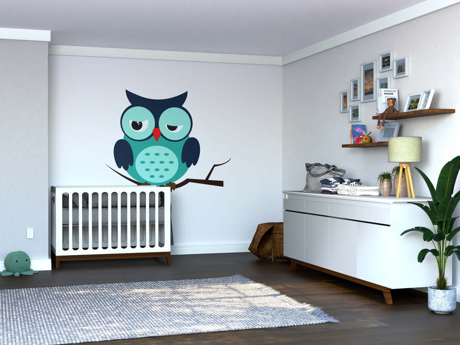 A modern nursery with a white crib, dresser, plant, and shelves with photos and toys. The Sleepy Blue Owl Wall Mural adds playful teal and blue charm. Wood floors and neutral walls complete the cozy vibe.