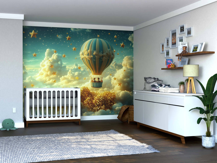 A nursery showcases the Starry Voyage Wall Mural with a hot air balloon among clouds and golden stars beside a white crib, along with a changing table, storage baskets, framed photos, shelves, a potted plant, and wooden floors.