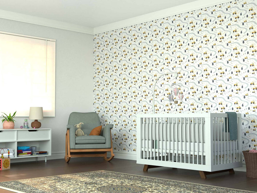 A cozy nursery with a white crib, the Tiny Tracks & Trucks Wall Mural, a green armchair with a stuffed bunny, a white shelf, lamp, and window blinds. A patterned rug covers the tidy wooden floor in softly lit comfort.