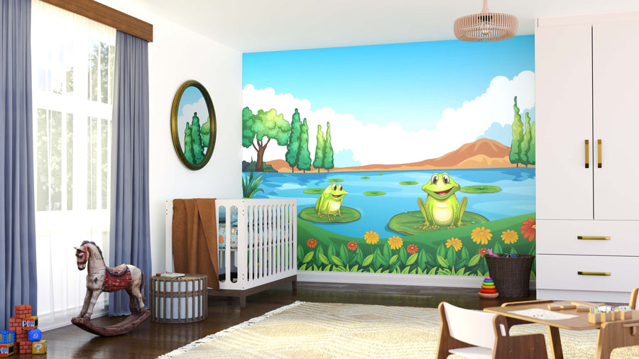 A bright nursery features a crib, rocking horse, toys, and the Waterside Frogs Wall Mural—two smiling frogs on lily pads in a pond with flowers, trees, and mountains under a blue sky—illuminated by natural light from a window.