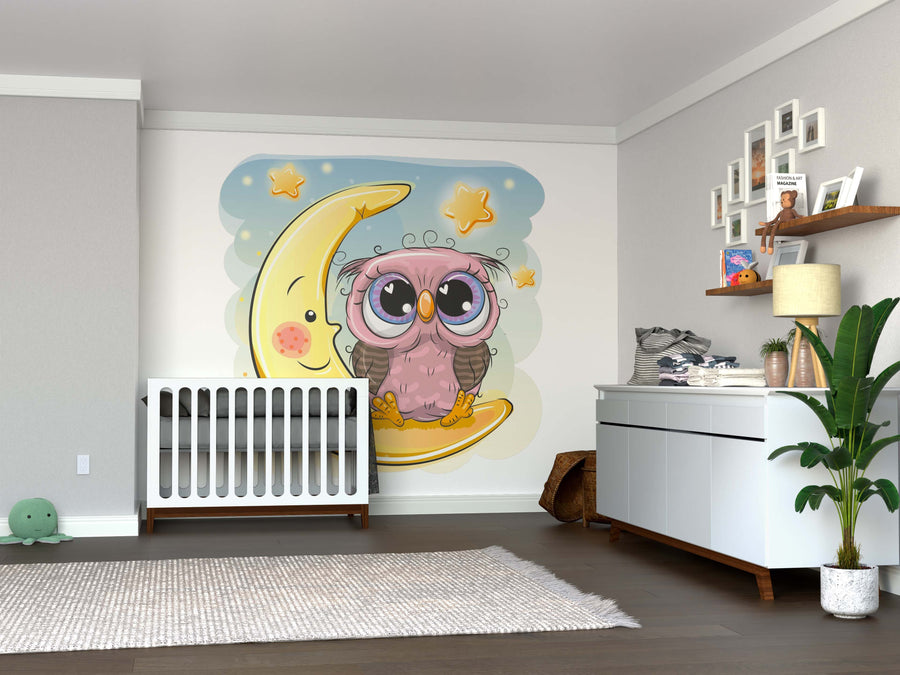 A nursery features the Wide-Eyed Owl Wall Mural showing a cute owl on a crescent moon with stars. Soft, neutral colors pair with a white dresser, gray rug, and playful décor. The removable wallpaper adds charm and versatility to the room.
