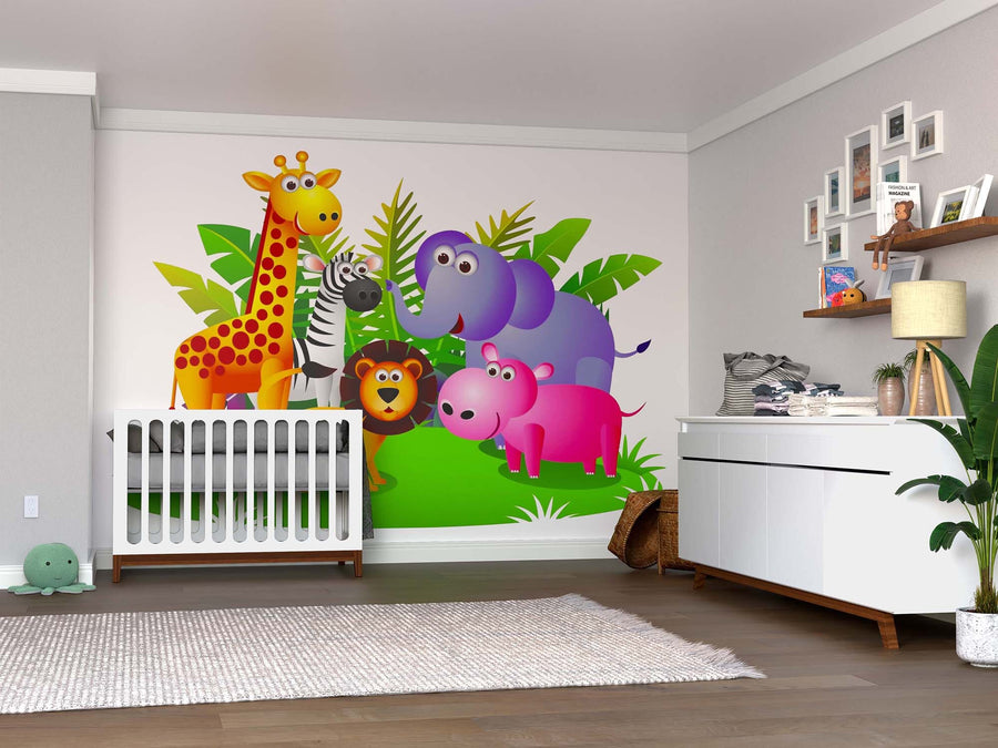 A nursery with wood floors features a crib beside the Wild Animal Collection Wall Mural, displaying colorful cartoon jungle animals among green leaves. White furniture, framed photos, plants, and soft toys complete the cozy room.