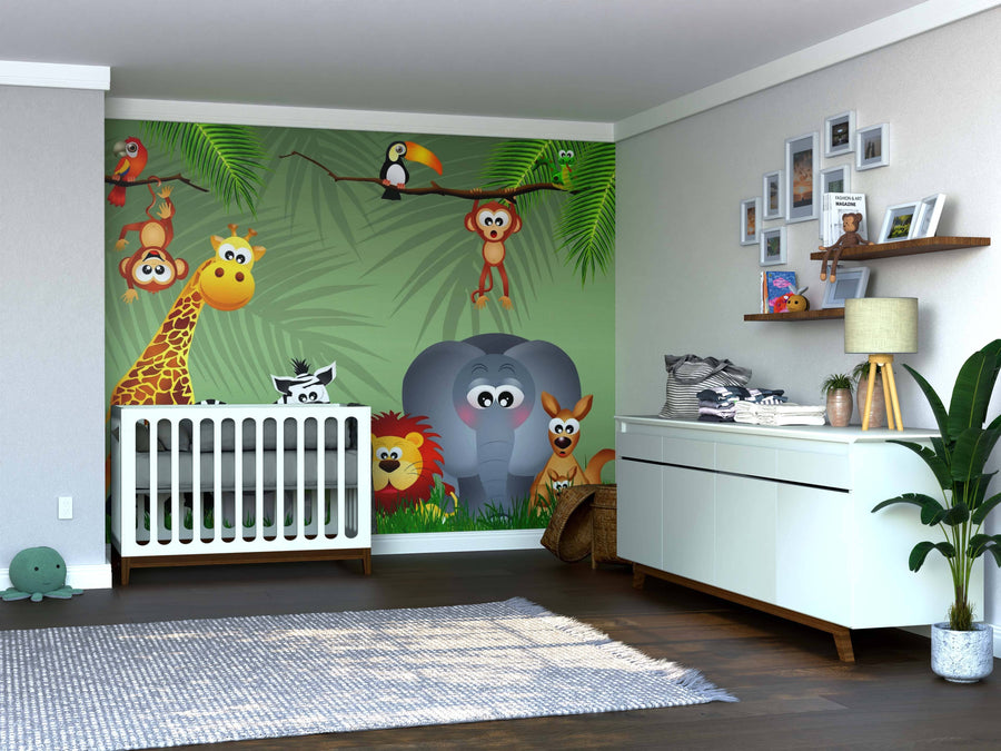 A nursery features a crib beside the Wildlife Fun Wall Mural with cartoon jungle animals—giraffe, lion, elephant, and monkeys. A white dresser and potted plant on wooden floors complete this space for peel and stick mural enthusiasts.