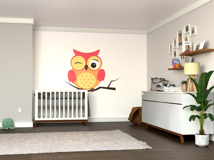 A cozy nursery featuring a white crib, the Winking Pink Owl Wall Mural, a dresser with a potted plant, shelves with toys and photos, a gray rug, and a plush turtle—all set against light walls and dark wood flooring.