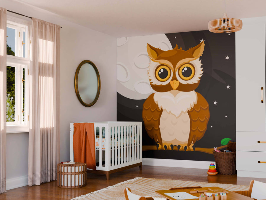 A cozy nursery features the Wise Moon Watcher Wall Mural—a custom peel and stick mural showing a wide-eyed cartoon brown owl against a nighttime sky—along with a crib, toys, soft decor, beige curtains, and a round mirror.