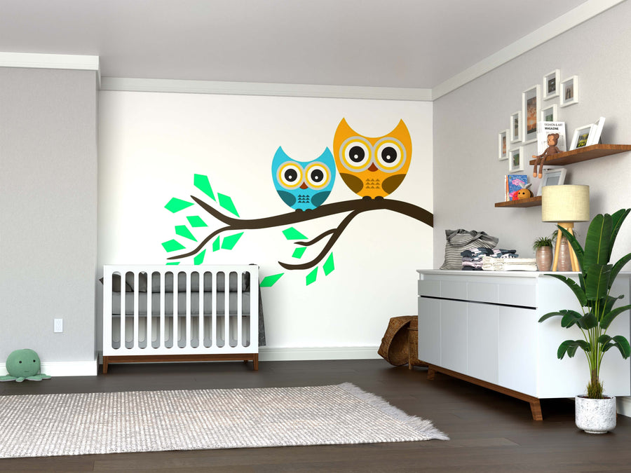A modern nursery features a white crib, dresser, and the Yellow and Blue Owl Wall Mural. Removable wallpaper, shelves with decor, a green plant, wooden floor, and soft lighting create a warm, cozy space for baby.