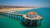 Transform your space with the Ocean View from Pier Wall Mural, a peel and stick wallpaper featuring a long pier, round red-roofed building, turquoise water, and a sandy beach. Easy to apply and remove for instant room refresh.