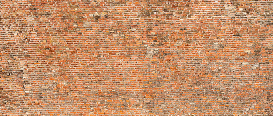 A modern open-plan living and dining area with wooden floors, blue armchairs, a gray sofa, a wooden dining table, globe pendant lights, a patterned rug, kitchen in the background, and an Old Red Brickwork Wall Mural as an accent.