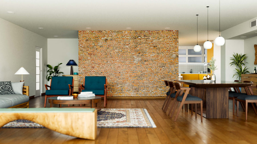 A modern open-plan living and dining area with wooden floors, blue armchairs, a gray sofa, a wooden dining table, globe pendant lights, a patterned rug, kitchen in the background, and an Old Red Brickwork Wall Mural as an accent.