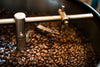A close-up of roasted coffee beans in a metal roaster, featured on the Perfect Batch Wall Mural. Ideal as custom printed or removable wallpaper to add warmth and texture to any space.