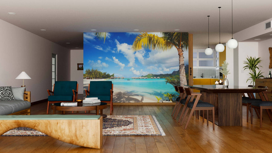 A modern living-dining room features wooden floors, mid-century furniture, and the Perfect Beach on Bora Bora Wall Mural, showcasing palm trees, blue sky, and turquoise water for a vibrant and relaxing indoor vibe.