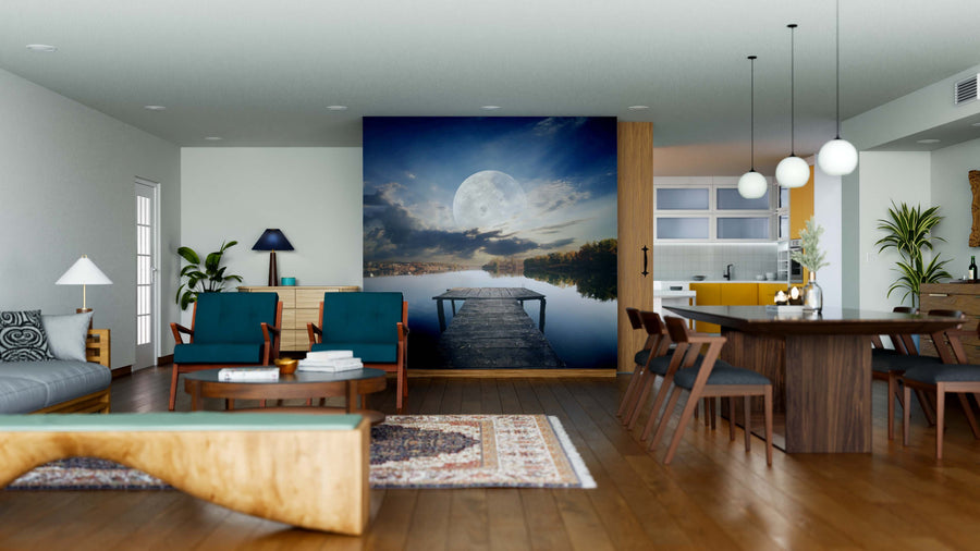 A modern open-plan living and dining area features wooden floors, teal chairs, a rug, pendant lights above the table, a kitchen with yellow cabinets, and a Pier Under the Moon Wall Mural as a stunning focal point.