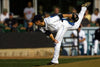 A pitcher in a white uniform and navy cap finishes his pitch on the mound, sunlight highlighting his form—captured in the Baseball 4 Wall Mural, perfect for adding stadium excitement to any room.