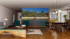A modern living-dining space with wooden floors, green chairs, a low coffee table, and dining set is enhanced by the Pontoon Beach and Resort Wall Mural, depicting a sunny beach with palm trees and huts for an open, breezy feel.