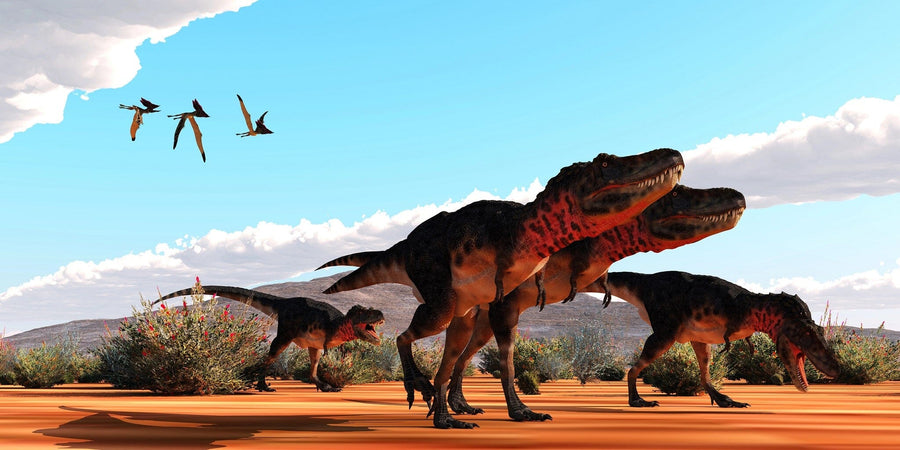 Dinosaurs with red and brown scales roam an orange landscape under a blue sky in the Prehistoric Hunt Wall Mural. Pterosaurs soar above, sparse bushes dot the ground, and distant hills are on the horizon.