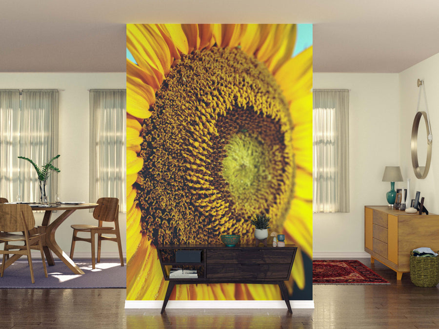 A modern living space is transformed by the vibrant Radiant Core Wall Mural featuring a sunflower on the accent wall, complemented by a wooden console table and decor, all bathed in natural light that highlights every stylish detail.