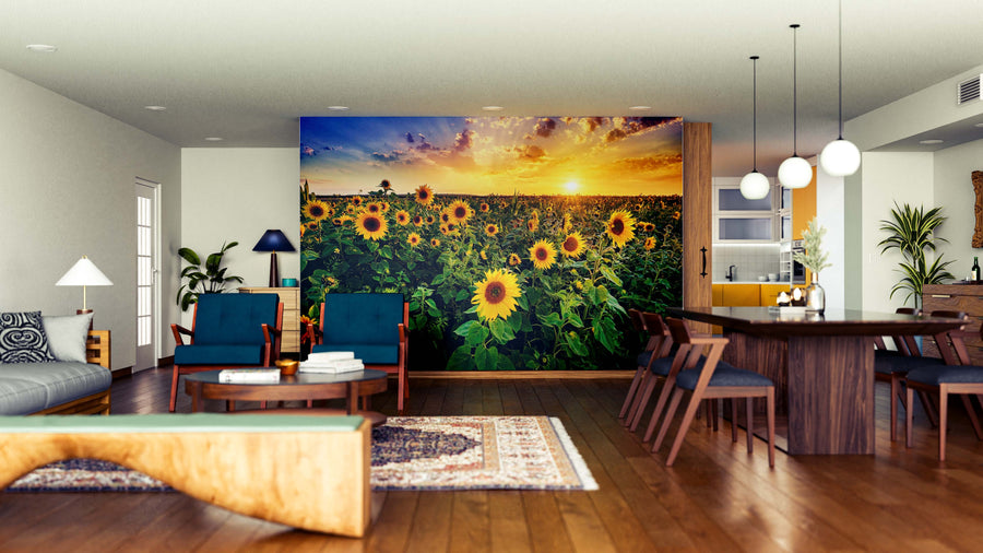 A modern open-concept living and dining area features wood floors, dark blue and wooden furniture, potted plants, pendant lights, and a large Radiant Evening Blooms Wall Mural of a sunflower field at sunset on the back wall.