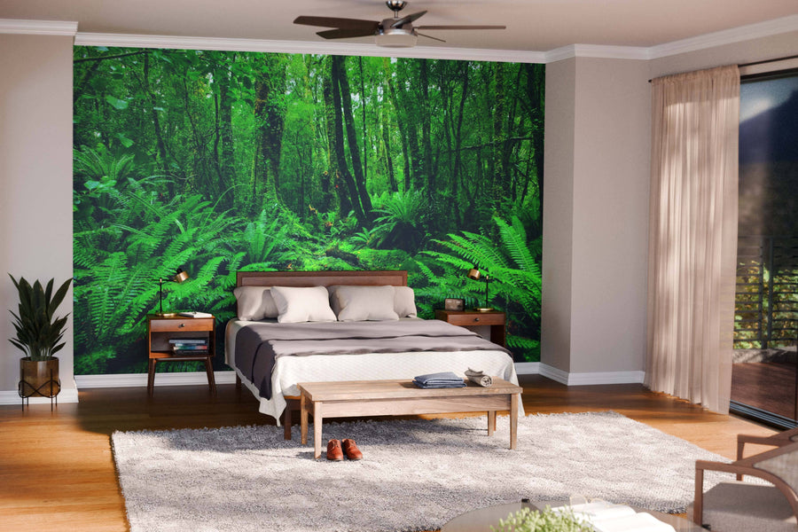 A modern living-dining space with wooden floors, mid-century furniture, and pendant lights features the Rainforest Fern Path Wall Mural as a lush green focal point, beautifully dividing the living area from the kitchen.