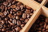 The Coffee 8 Wall Mural features a close-up of dark brown, glossy roasted coffee beans in a wood divider—perfect as custom printed or removable wall decor to create an inviting atmosphere for any coffee lover’s space.