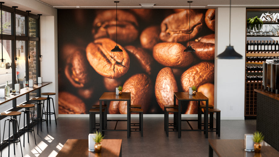 A modern coffee shop features wooden tables and stools, tall windows to the left, a counter with shelves of bottles on the right, and a "Roasted to Perfection Wall Mural" of coffee beans. Small plants decorate each table.
