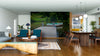 A modern open-plan living and dining area with wooden floors and furniture features the Rowboat Rest Wall Mural on the back wall, depicting a dock leading to a rowboat on a calm lake, bringing serene nature indoors.