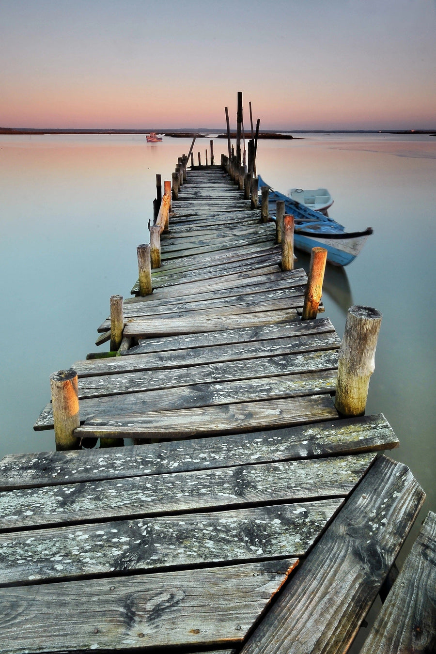 A modern living space highlights the Rustic Dock Wall Mural, showing a wooden pier at sunset with a boat. Wooden furniture, greenery, and a round mirror enhance the cozy vibe and complement the mural’s tranquil setting.