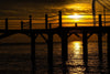 The Silhouetted Pier Glow Wall Mural features a wooden pier in silhouette over calm water at sunset, with orange and yellow skies reflected on the water—an easy peel and stick mural ideal for adding tranquil beauty to any room.