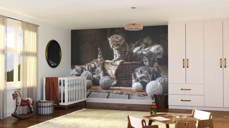 A cozy nursery with a crib, toys, and a rocking horse features the Snuggly Basket Babies Wall Mural. Sunlight streams through sheer curtains onto a wardrobe, basket, and round mirror for a playful, inviting atmosphere.