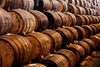 The Stacked Wooden Barrels Wall Mural by Deposit photo captures a rustic, aged atmosphere with dark brown barrels featuring visible grain and metal bands, reminiscent of wine or spirits storage. This peel-and-stick wall mural showcases a uniform pattern perfect for adding character to any space.