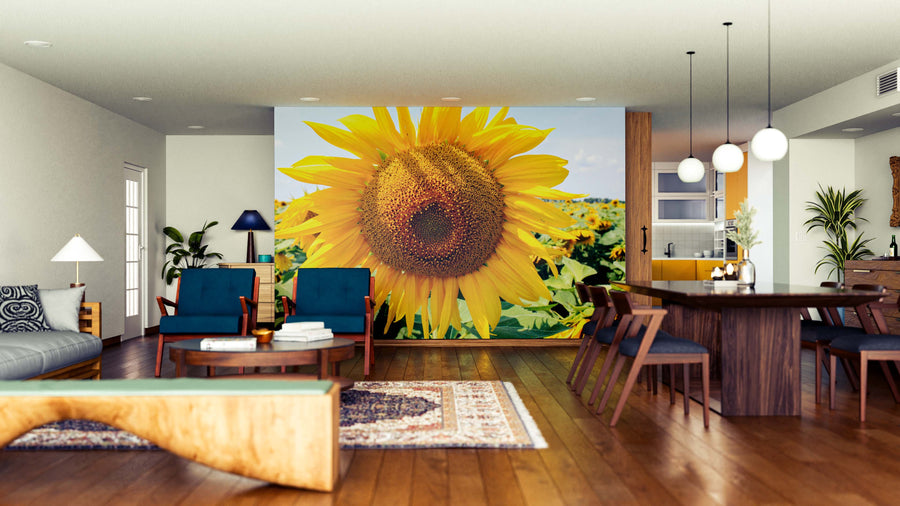 A modern open-plan living and dining area features wooden floors, mid-century furniture, and a Sun-Kissed Sunflower Wall Mural. The kitchen is visible in the background, with pendant lights above the dining table.