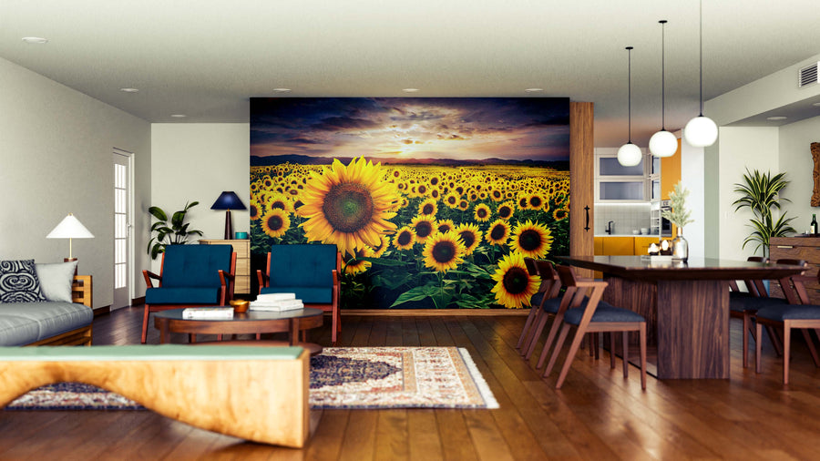 A bright, modern living-dining room with wood floors, blue and wooden furniture, and an area rug features the Sunflower Fields Forever Wall Mural, depicting a vibrant sunflower field at sunset for added color and depth in the open space.