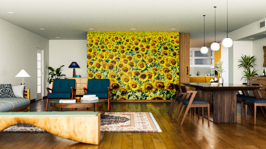 A modern living and dining area with wood floors, dark blue chairs, a sofa, and the Sunflower Sea Wall Mural adds vibrant yellow color. Pendant lights hang above the table as sunlight fills the space.