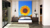 A modern bedroom features a large Sunflower Wall Mural behind the bed. White bedding rests between dark nightstands with lamps, and sunlight streams through glass doors on the left, casting shadows on the light rug and floor.