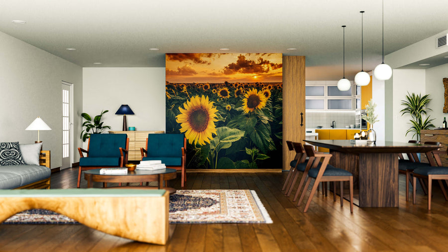 Modern open-plan living and dining space with wood flooring, dark blue and wood furniture, pendant lights over the dining table, and a striking Sunflowers Wall Mural under a sunset sky; the kitchen can be seen in the background.