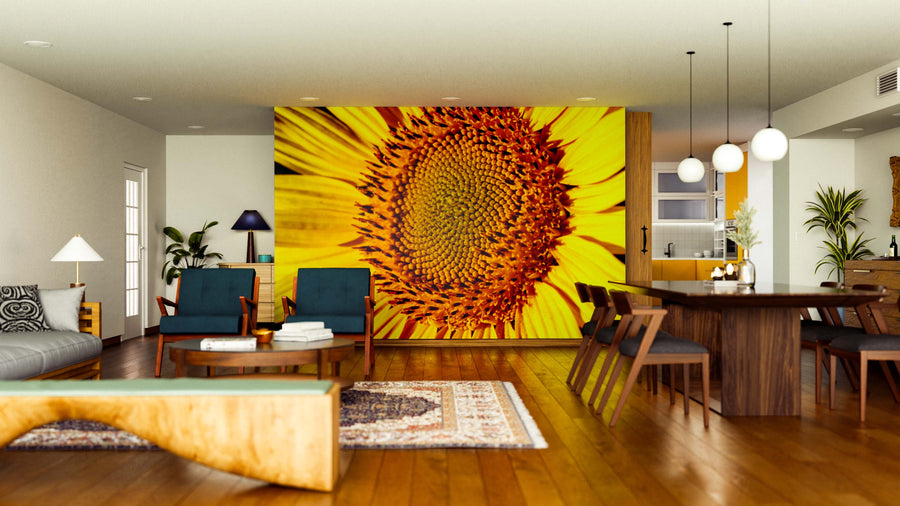 A modern living-dining room features wood floors, mid-century furniture, and the Sunny Center Wall Mural with a large sunflower. Pendant lights hang above a dark dining table, while plants and rugs brighten the open space.