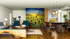 A modern open-concept living and dining room with wood floors, dark blue chairs, and a unique coffee table features the Sunrise Over Sunflowers Wall Mural, adding vibrant color and a stunning nature-inspired focal point to the space.