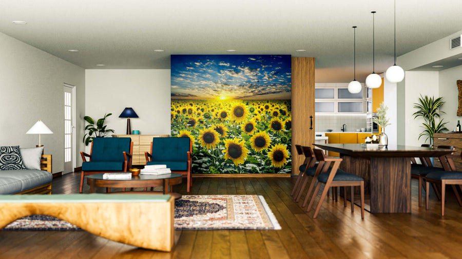 A modern open-concept living and dining room with wood floors, dark blue chairs, and a unique coffee table features the Sunrise Over Sunflowers Wall Mural, adding vibrant color and a stunning nature-inspired focal point to the space.