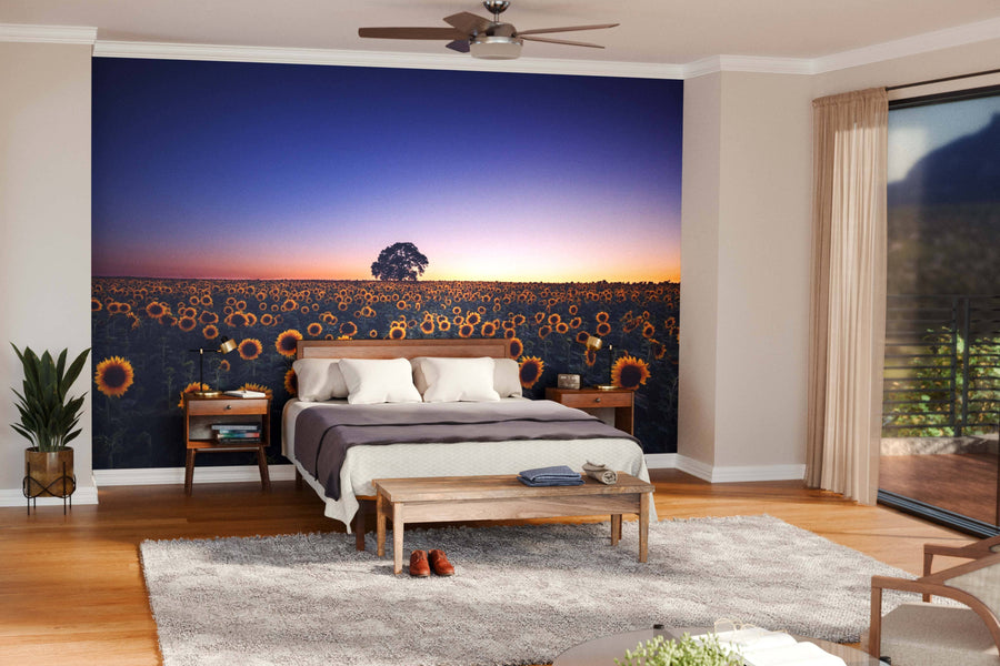A modern open-plan living and dining room with wooden floors, stylish furniture, and the Sunset Over Sunflower Field Wall Mural as a peel and stick accent, creating a warm, artistic focal point in the cozy, well-lit space.