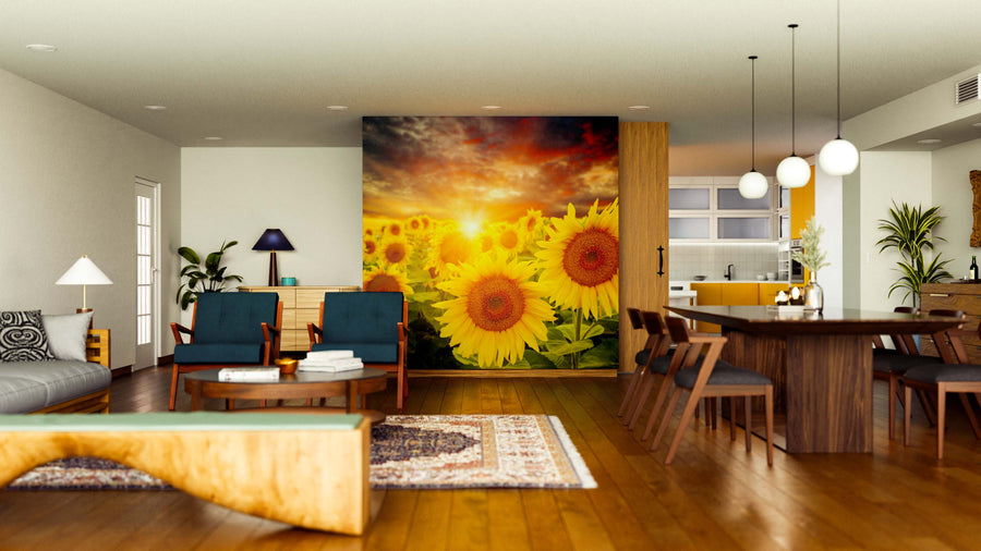 A modern, open-concept living and dining room with wood floors, mid-century furniture, pendant lights, and a striking Sunset Over Sunflowers Wall Mural, with a cozy kitchen visible in the background.