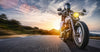 A motorcyclist in a black helmet rides along a winding road, their headlight glowing, echoing the adventurous spirit of the Sunset Ride Rush Wall Mural, showcasing vibrant sunset hills and capturing the dynamic beauty of the open road.