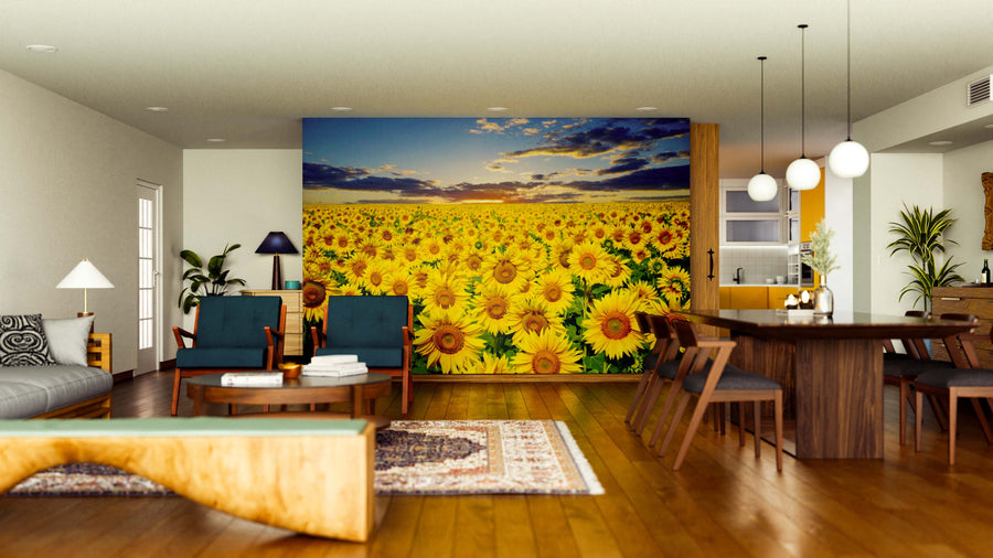 A modern living and dining room with wooden floors and stylish furniture features the Sunset Symphony Wall Mural, showcasing a sunflower field at sunset. Warm lighting and a cozy atmosphere complete this stunning space.