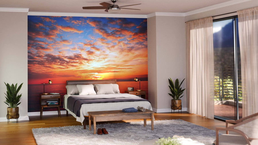 A modern living-dining room with wooden floors, teal chairs, a wooden table, pendant lights, and the "Sunset at the Sea Wall Mural," featuring a vibrant orange sunset over the ocean for a warm, inviting touch.