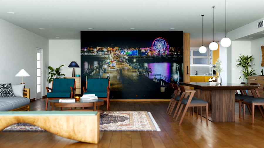 Modern living and dining room with wood floors, contemporary furniture, and indoor plants. The Santa Monica Pier Wall Mural showcases a vibrant night scene, adding color and depth to the neutral-toned space.