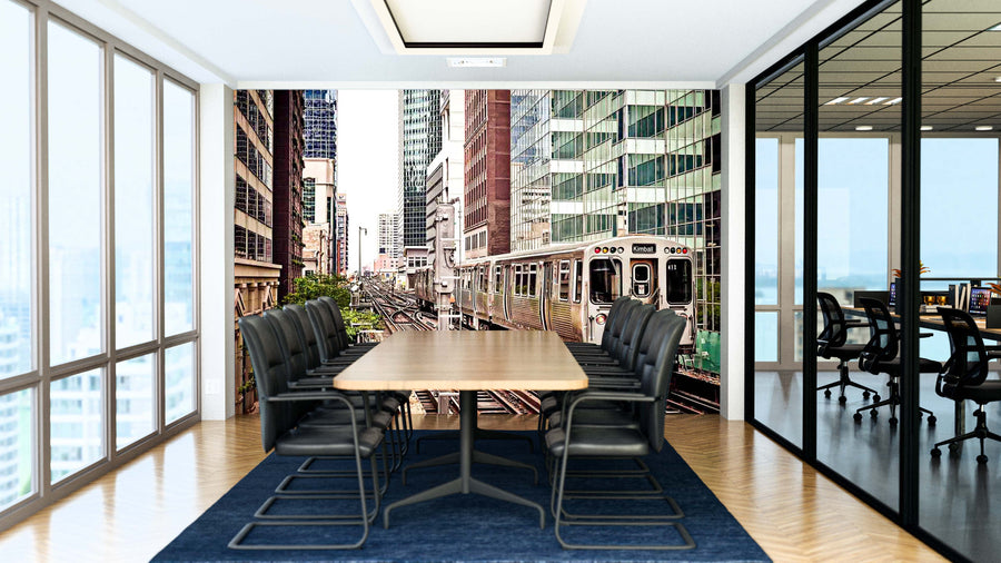 A modern conference room with a long wooden table, black chairs, and glass walls. The back wall displays the "Train Moving On The Tracks Wall Mural," showing elevated train tracks, tall buildings, and a train passing through the city.