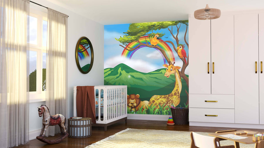 A bright nursery features the Tropical Animal Fun Wall Mural, showing a giraffe, lion, and parrots under a rainbow with green mountains. A white crib, rainbow stacking rings, wooden horse, and woven basket complete the cozy space.