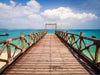 The Pier 9 Wall Mural showcases a wooden pier over turquoise waters leading to a square frame, with fluffy clouds in a bright blue sky reflecting off the serene scene. Boats dot the horizon, logs, and rope railings adding rustic charm—like entering your own custom-printed paradise.