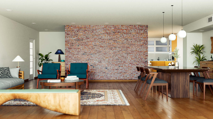 A spacious living-dining area with wooden floors, a Typical Red Bricks Wall Mural, teal armchairs, a gray sofa, wooden dining table and chairs, pendant lights, a kitchen backdrop, minimalist decor, and a patterned rug.